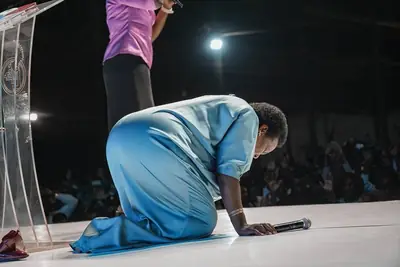 A young woman bowed in prayer on the stage